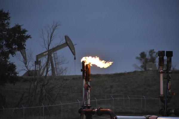 A flare to burn methane from oil production is seen on a well pad near Watford City, North Dakota, Aug. 26, 2021. 