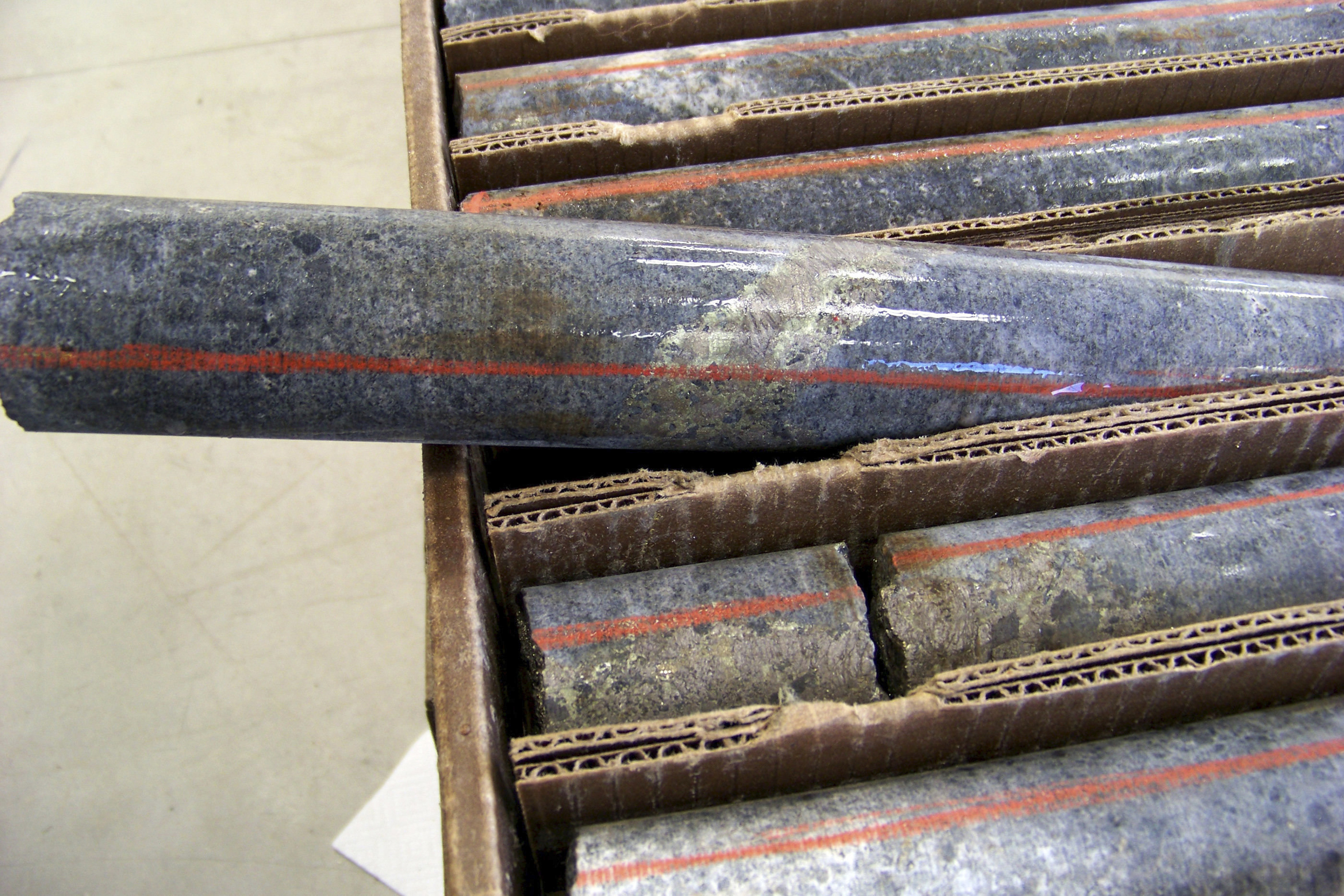 A box of core samples showing a band of shiny minerals containing copper, nickel and precious metals.