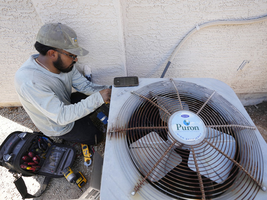 A technician works on an air conditioning unit in Phoenix.