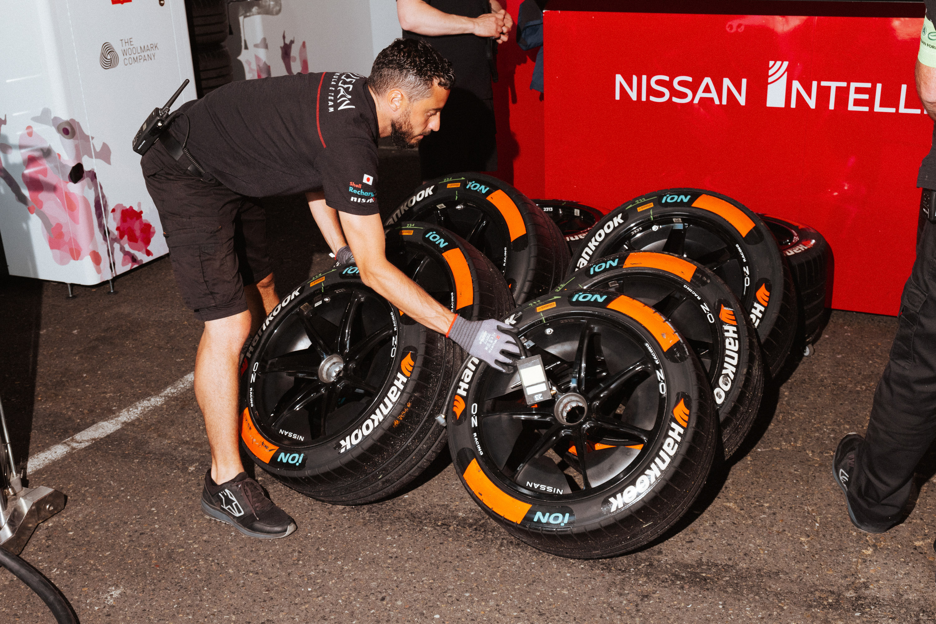 A pit crew member handles tires in the garage before the start of a Formula E race.