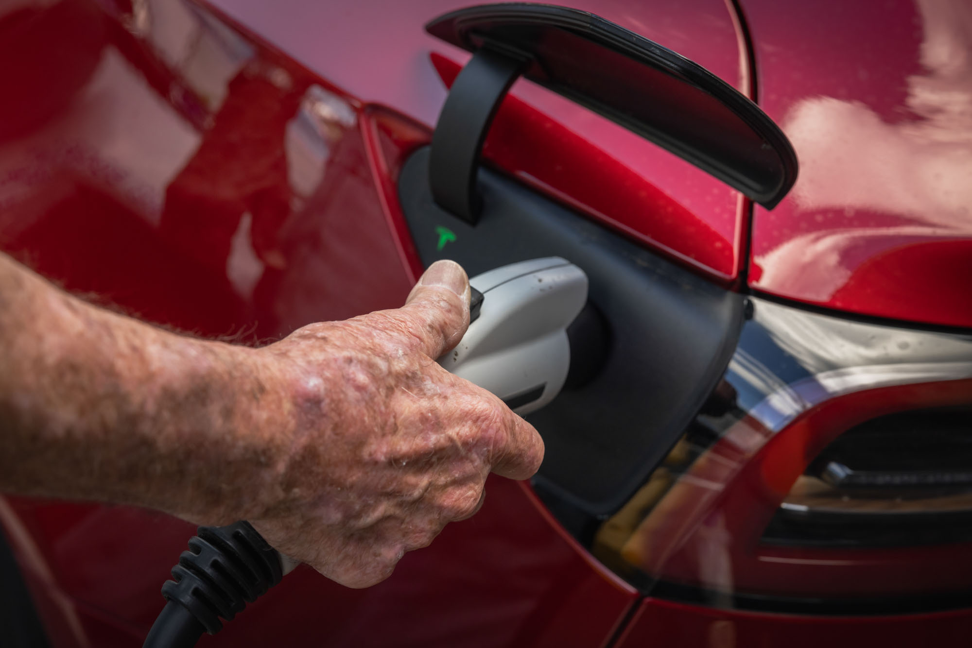 A person attaches a charger to a Tesla.