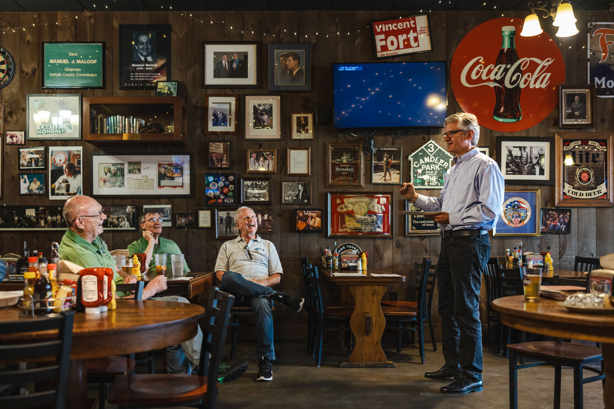 Chris Campbell (right) speaks to a group of three men in a tavern.